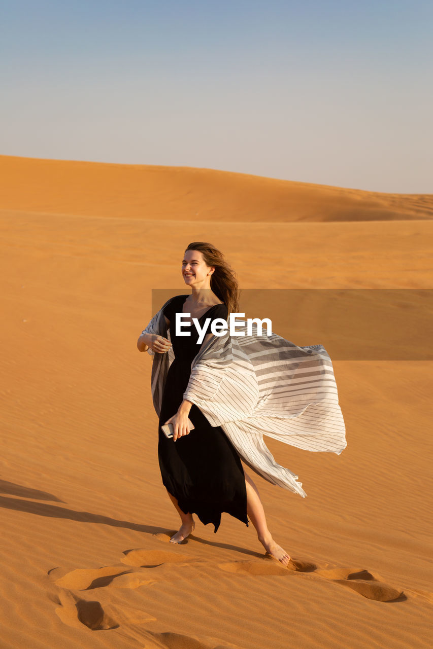 Full length of young woman on sand dune in desert