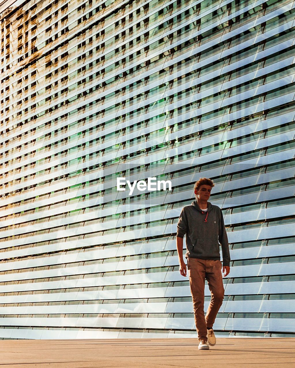 FULL LENGTH PORTRAIT OF A MAN STANDING AGAINST WALL