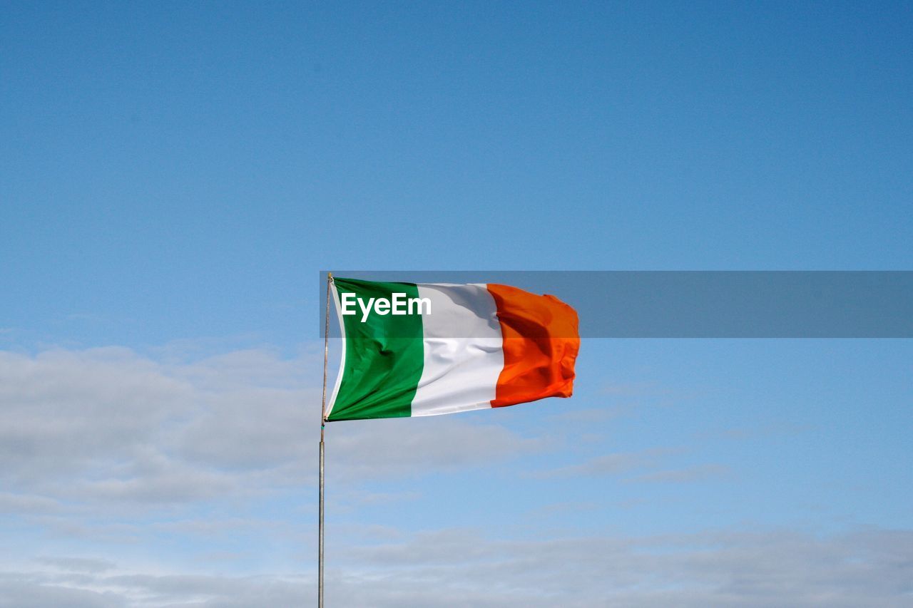 Low angle view of flag waving against blue sky during sunny day