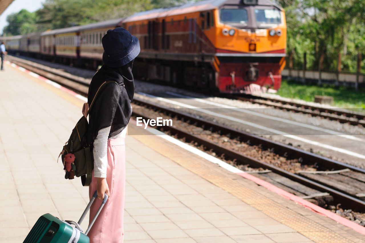 rear view of man walking on railroad station platform