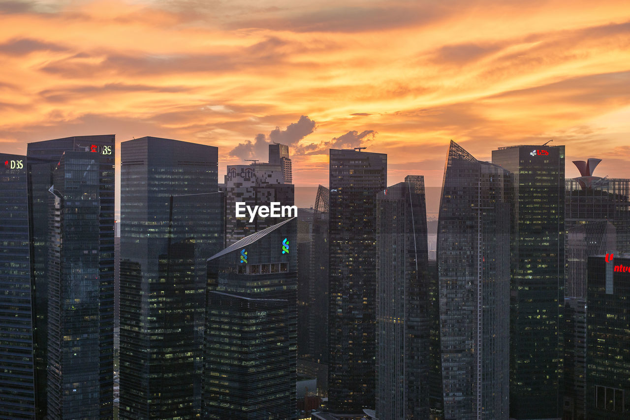 Modern buildings in city against orange sky