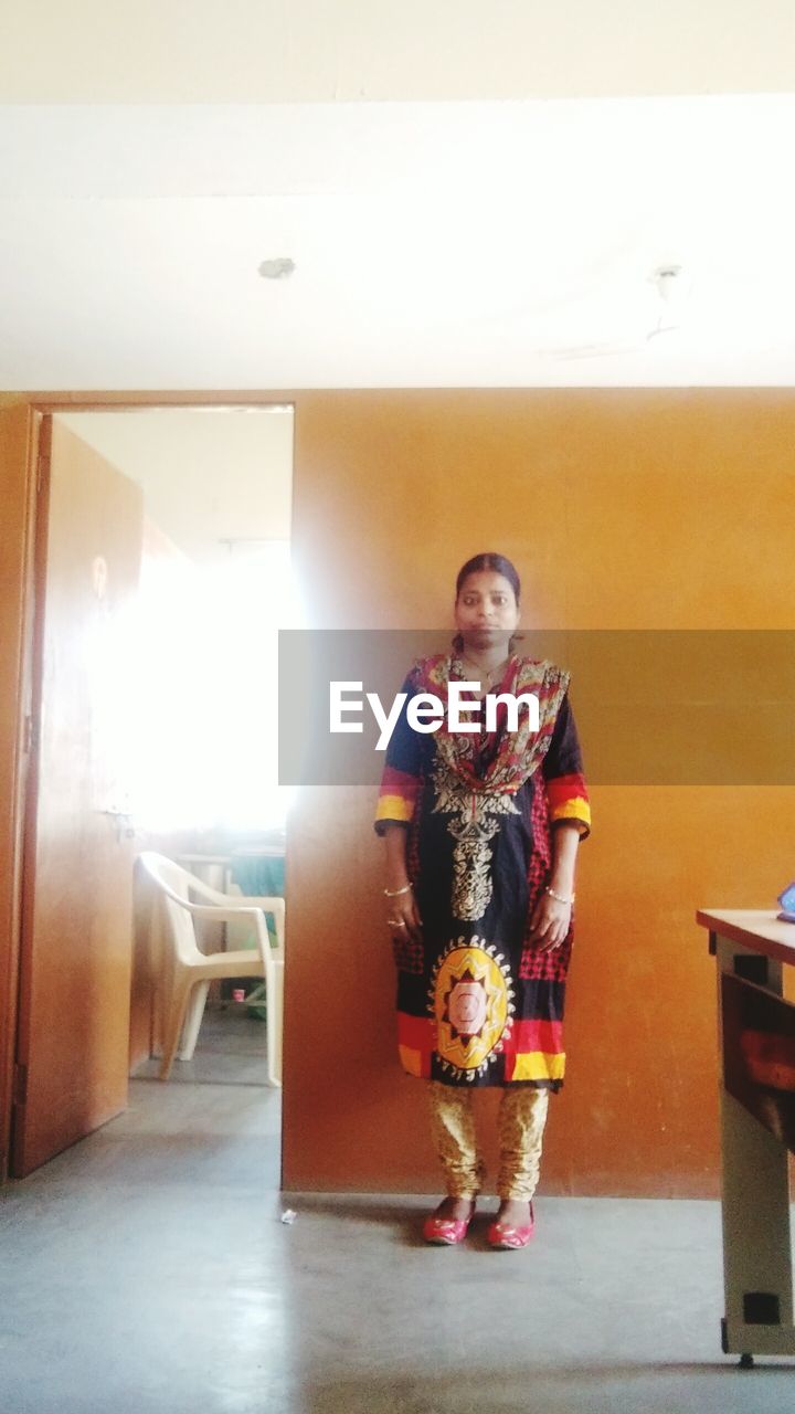 PORTRAIT OF BEAUTIFUL YOUNG WOMAN STANDING IN CORRIDOR