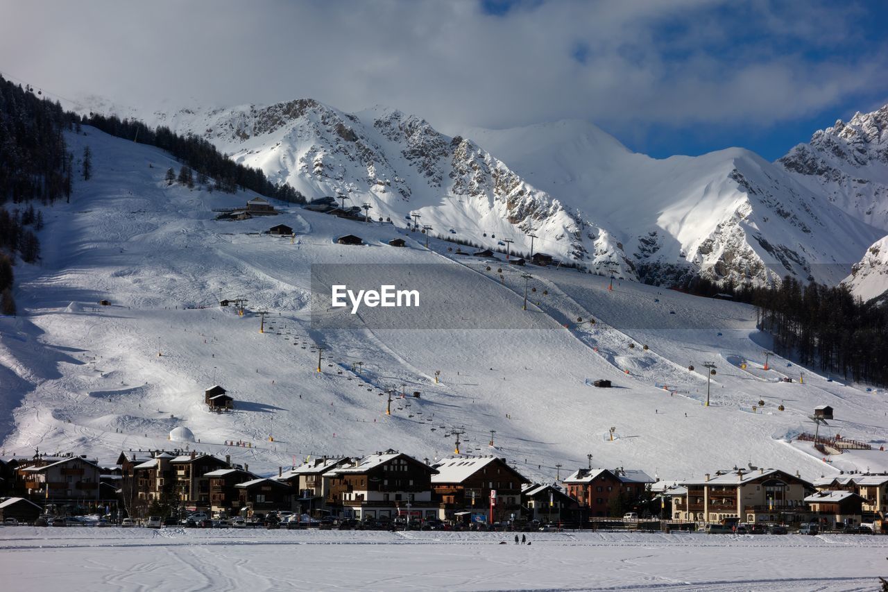 Scenic view of snow covered houses by mountains against sky