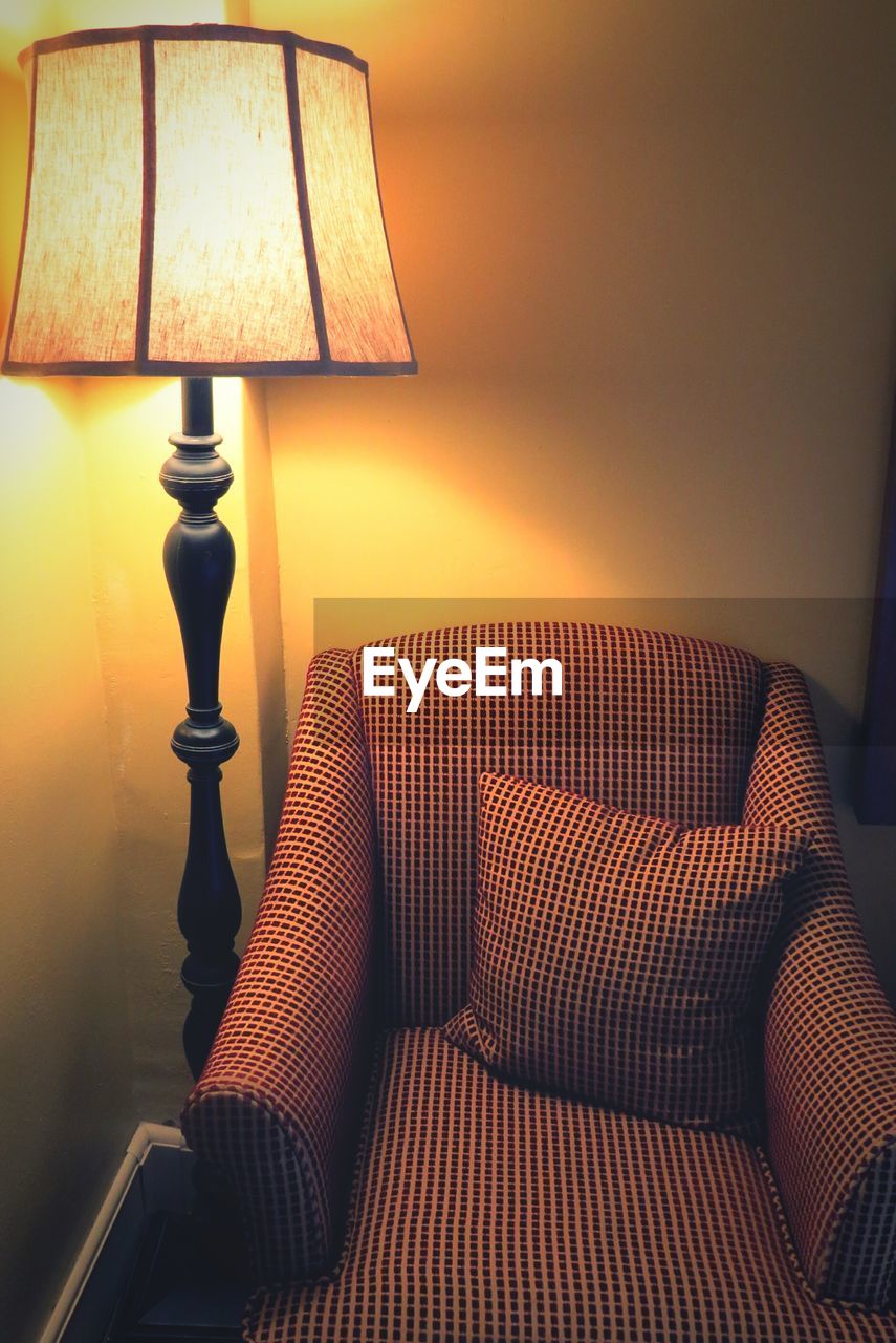Close-up of electric lamp by chair