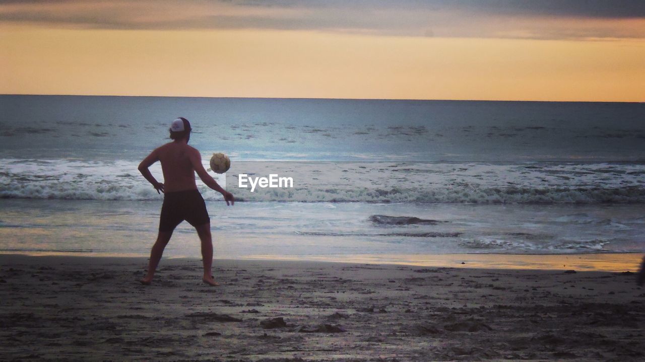 FULL LENGTH OF MAN WALKING ON BEACH AGAINST SKY