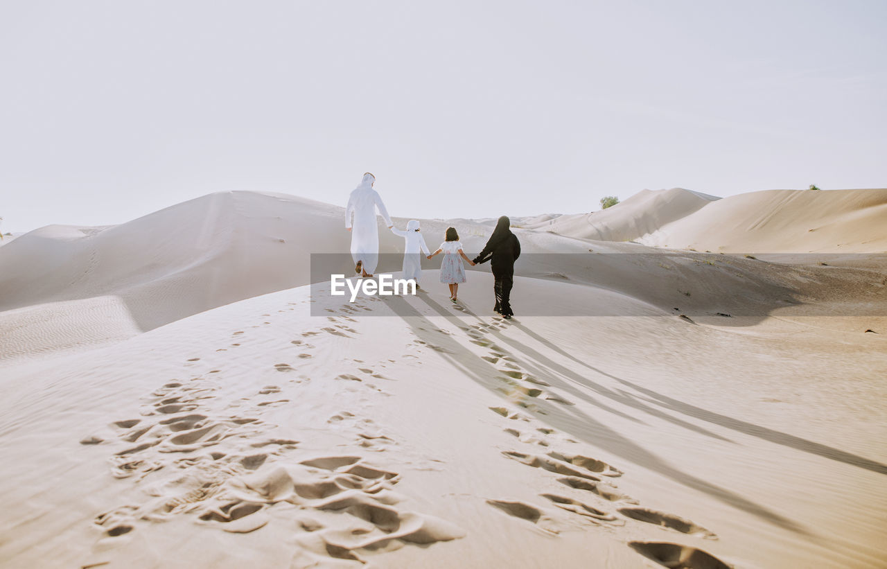 Rear view of family walking on sand dune