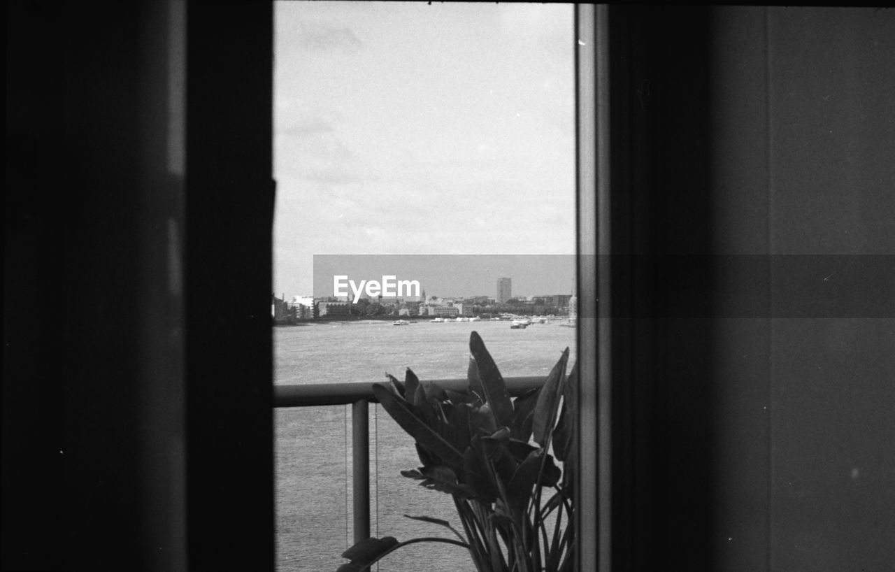 CLOSE-UP OF CITYSCAPE AGAINST SEA SEEN THROUGH WINDOW