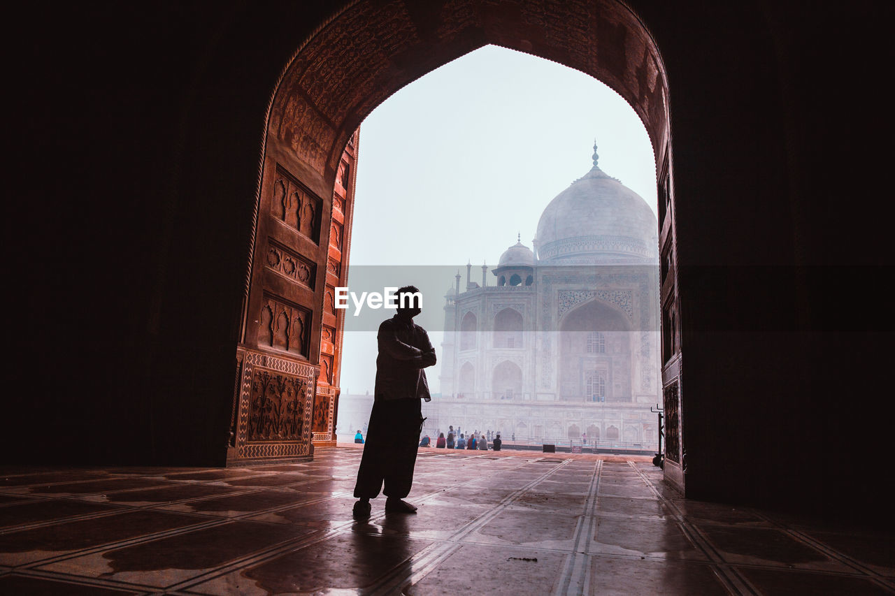 Silhouette man standing by arch against taj mahal
