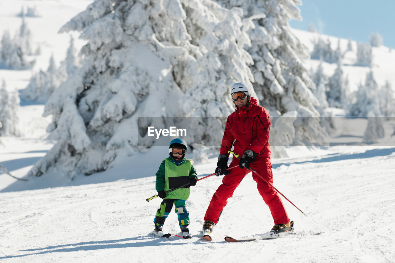 Full length of father and son skiing on snow during winter