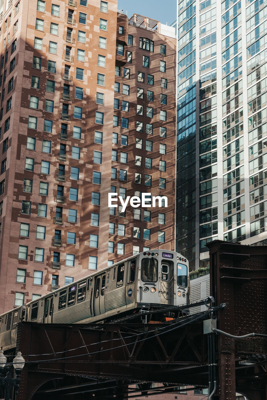 Train on railroad tracks by buildings in city