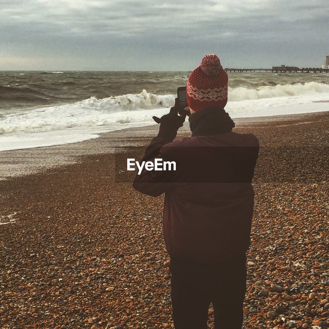 Rear view of woman photographing sea against sky