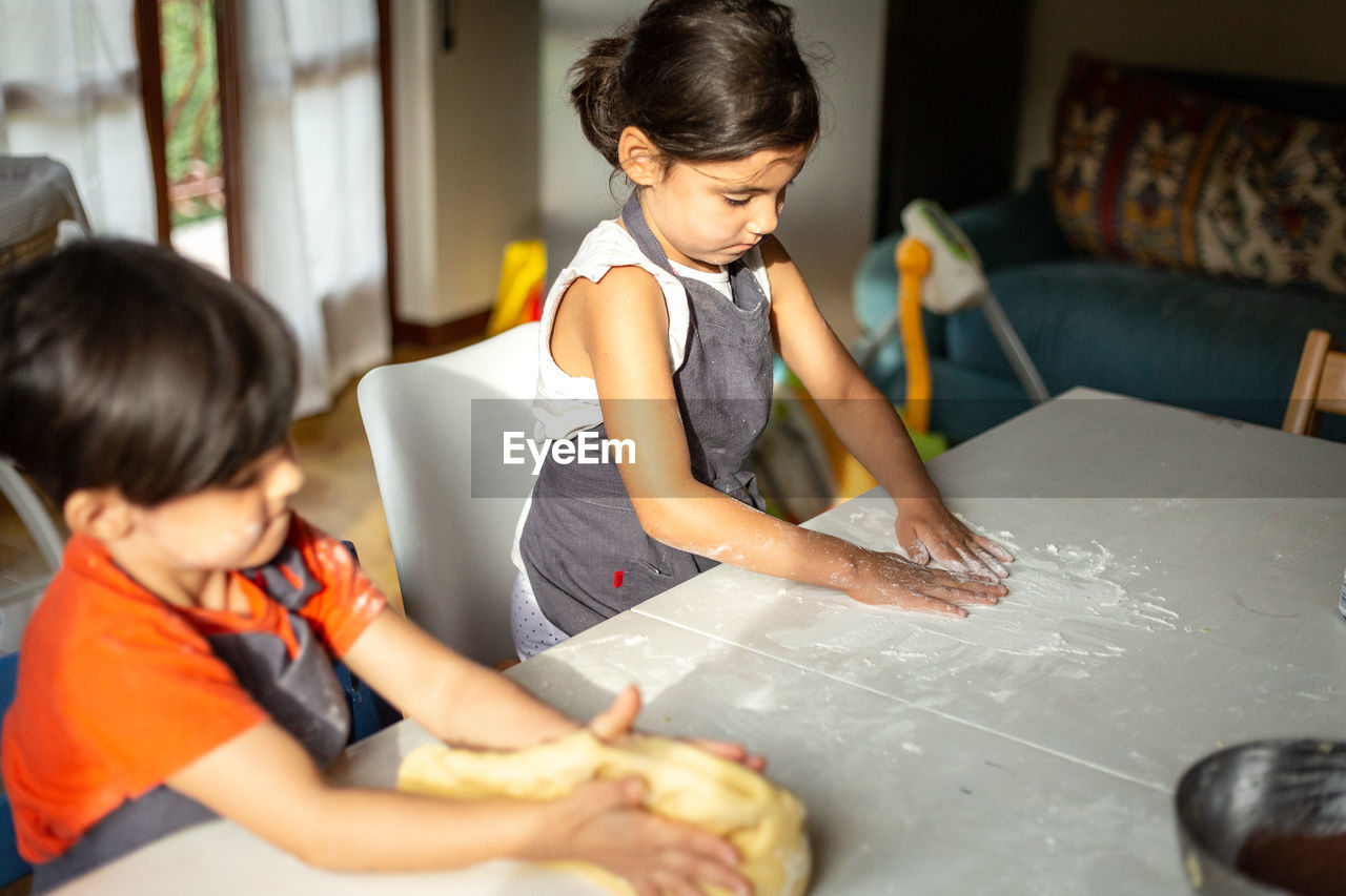 Two concentrated girls preparing the food at white table