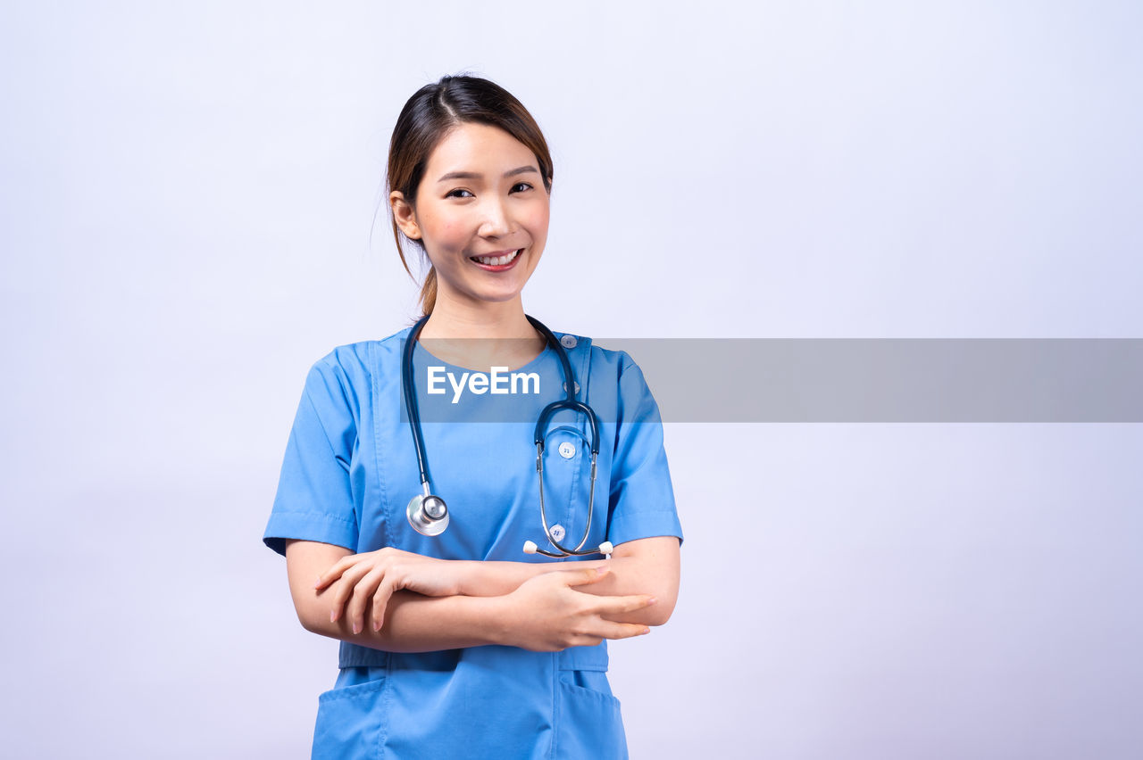 PORTRAIT OF SMILING YOUNG WOMAN AGAINST WHITE BACKGROUND