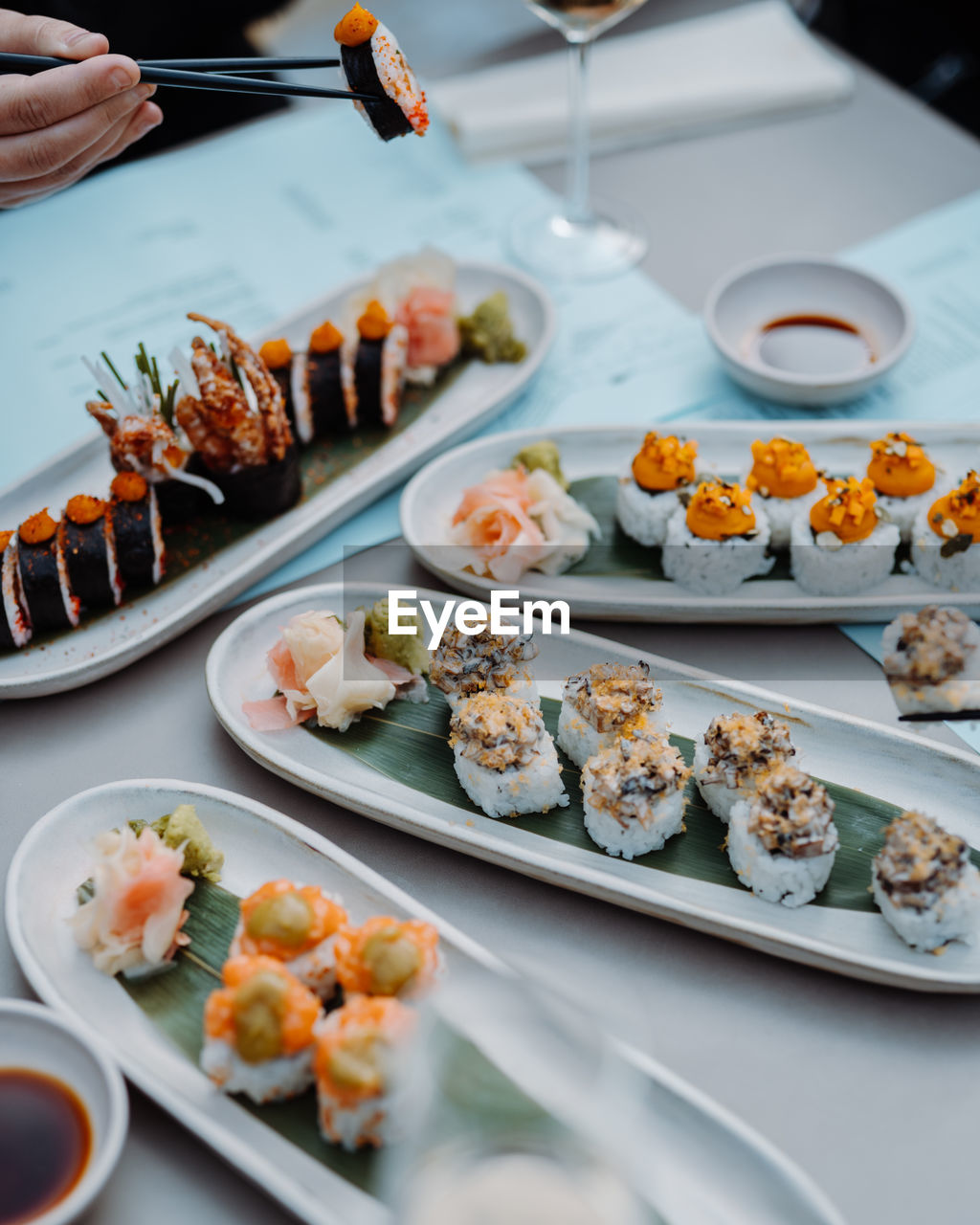 Man hands holding sushi and rolls with wooden chopsticks at the restaurant