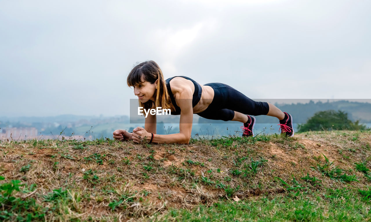 Young female athlete training doing plank outdoors