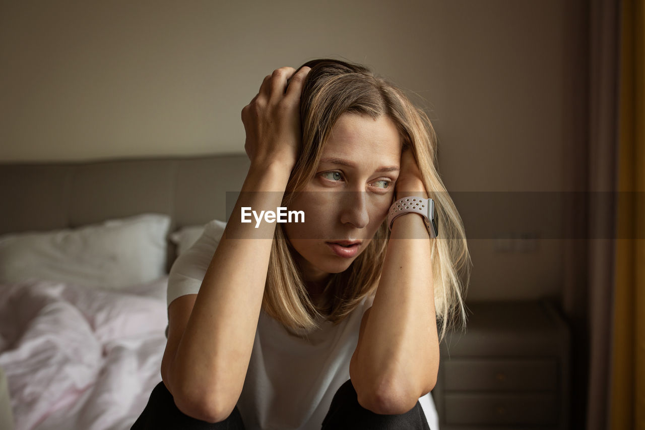 Depressed woman sitting on bed at home