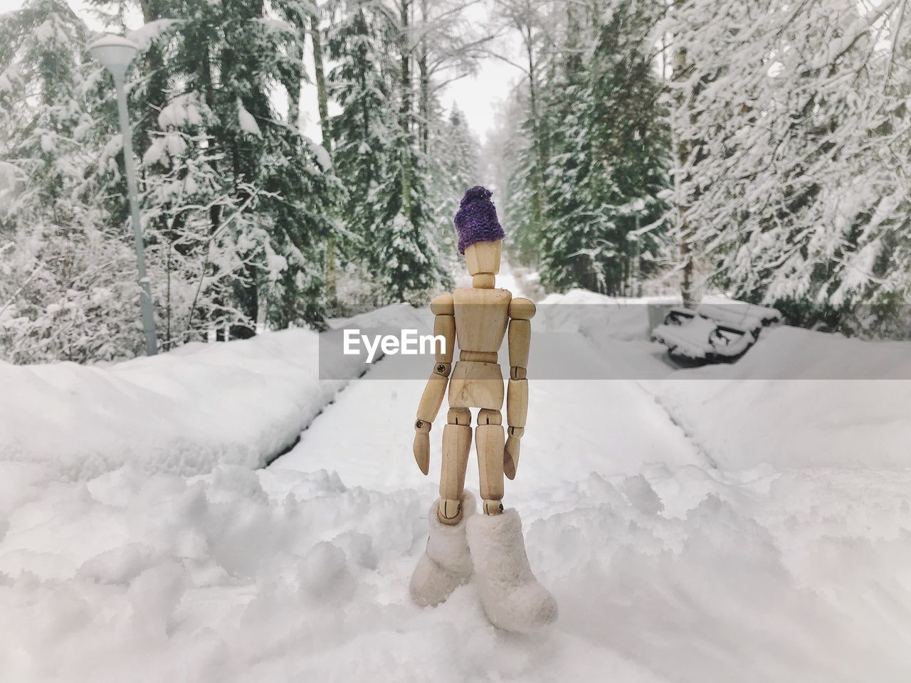 Figurine on snow covered field against trees