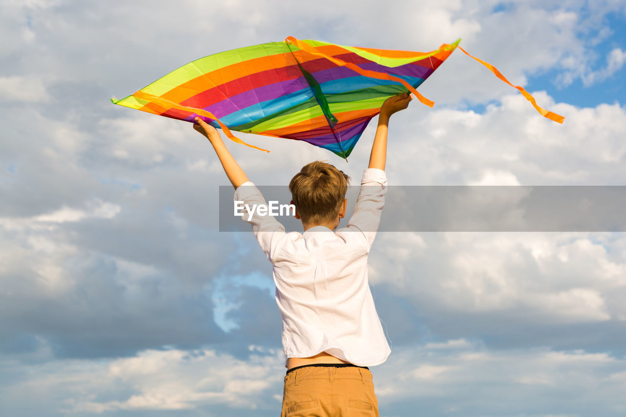 Portrait of a child 8-9 years old with kite. a blond boy stands and looks distance from a  mountain.