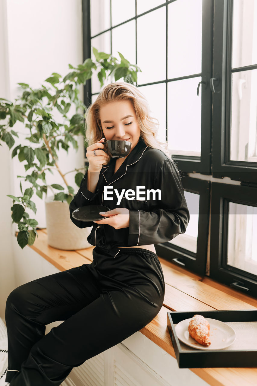 Beautiful happy smiling girl enjoying and having breakfast in bed in the morning in a cozy home