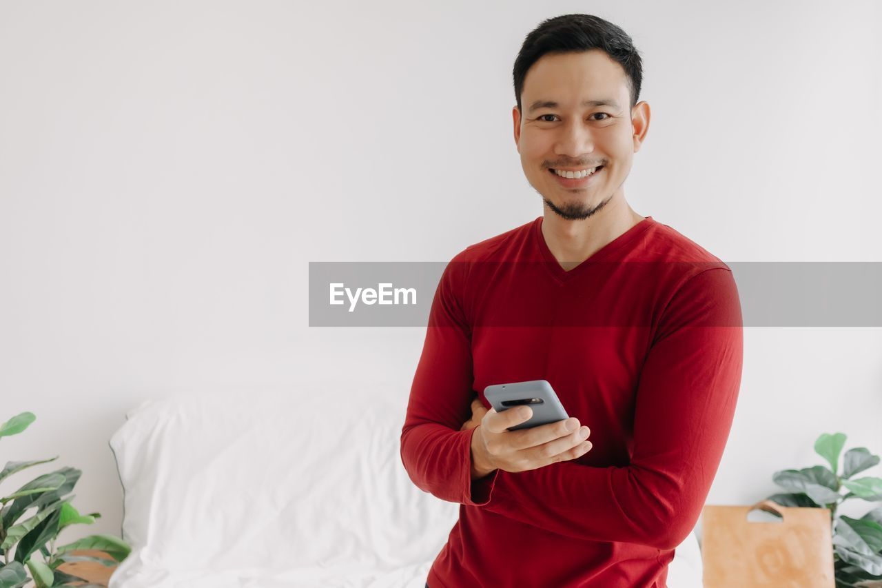 young man using mobile phone while sitting on bed