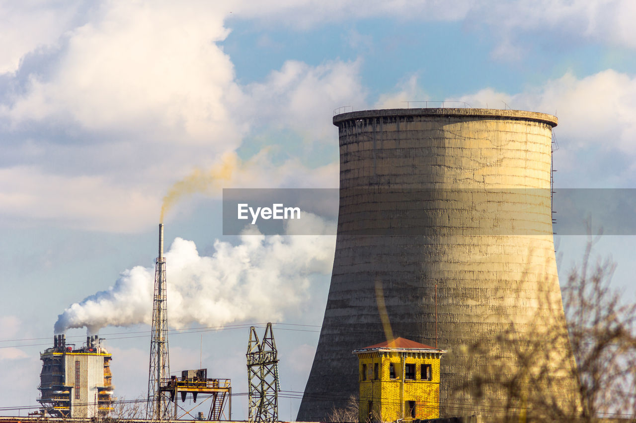 Smoke stacks emitting pollution against sky