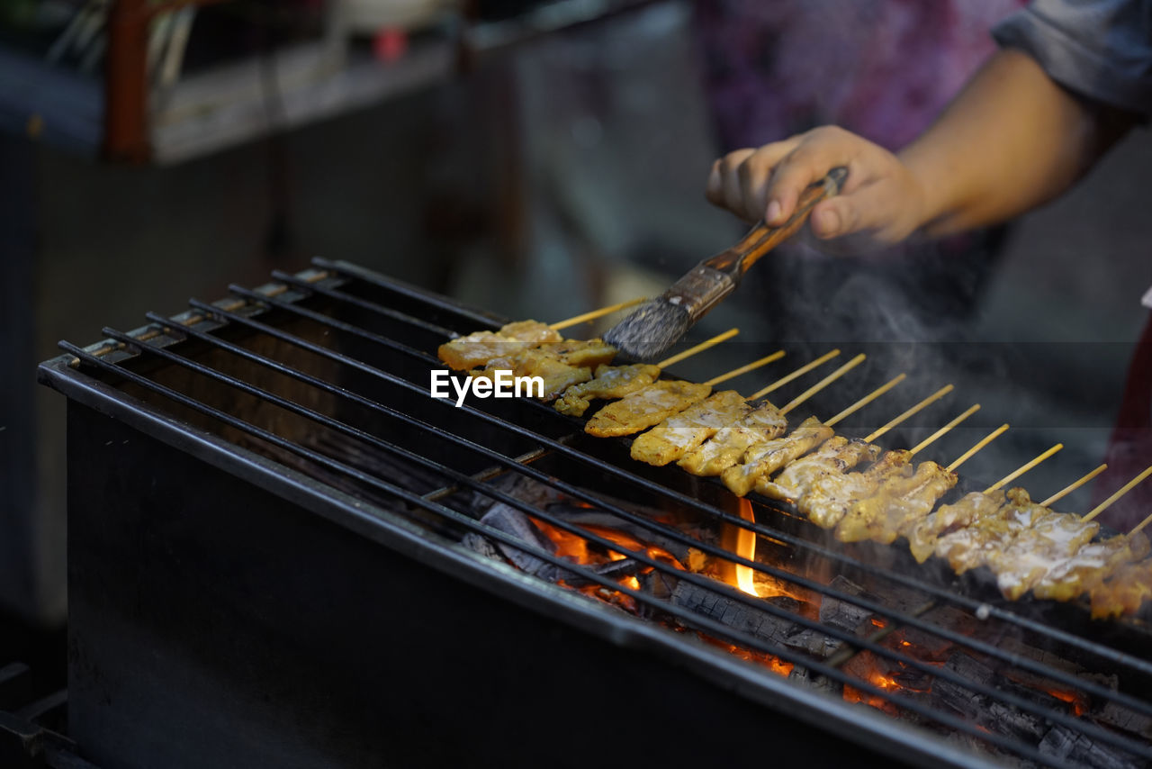 MIDSECTION OF MAN PREPARING FOOD ON BARBECUE