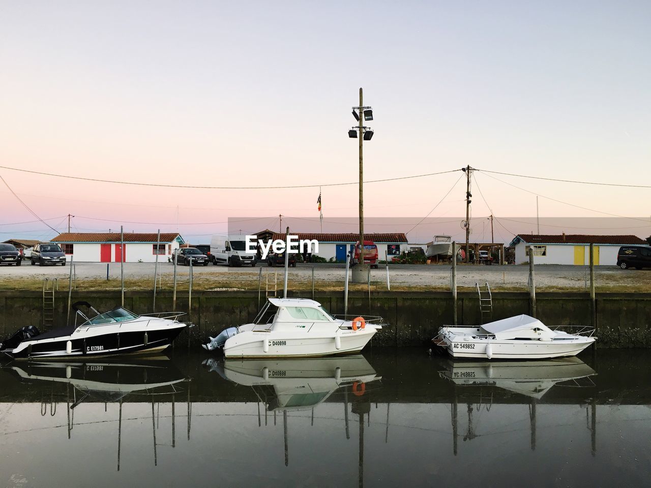 Boats moored at harbor against sky during sunset