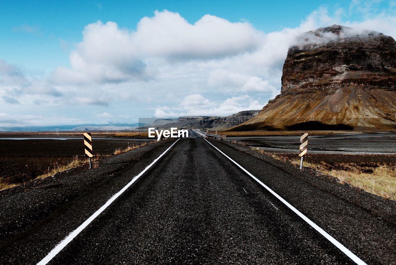 Empty road against cloudy sky