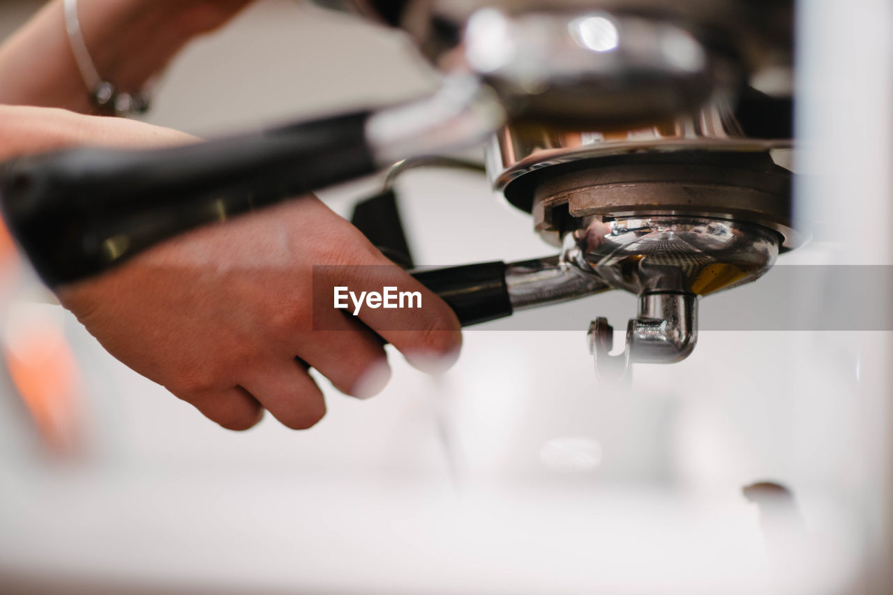 Cropped hands of woman making coffee in cafe