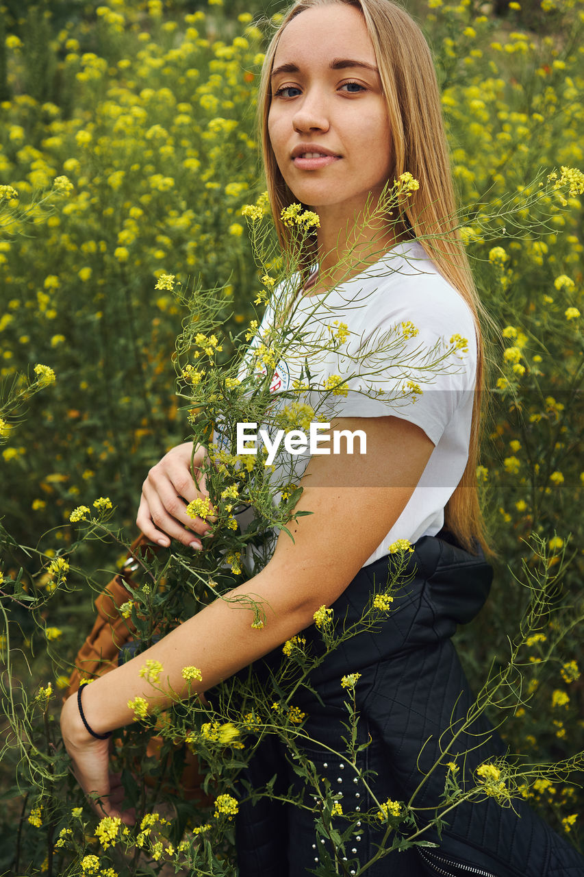 Beautiful young woman with yellow flower in field