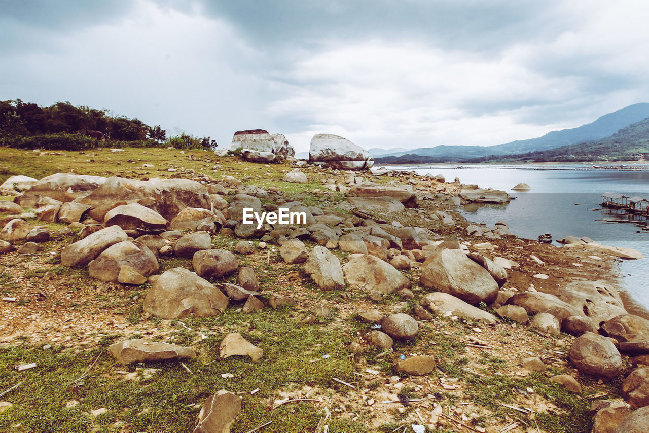 Rocks on shore by sea against sky