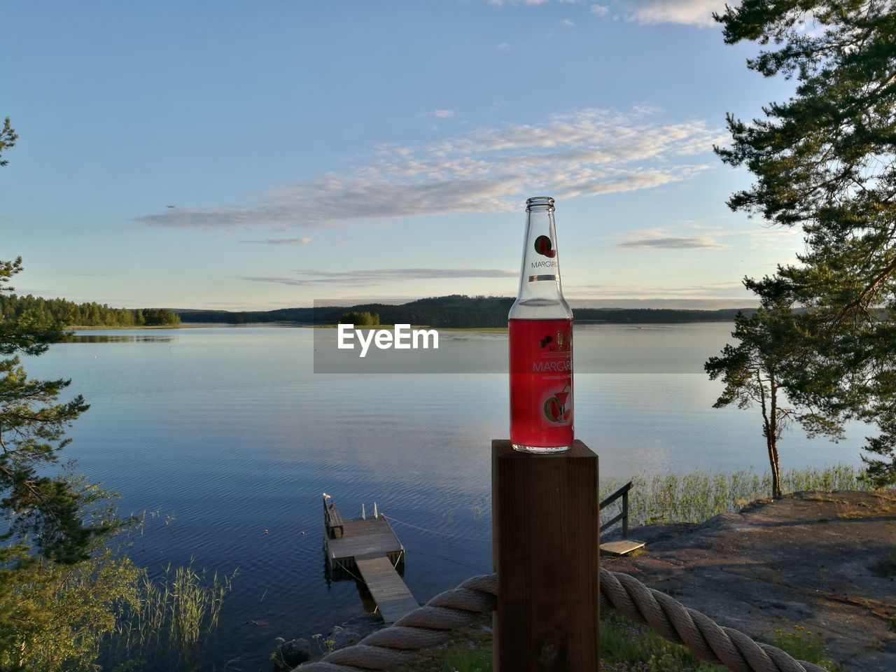 WOODEN POST BY LAKE AGAINST SKY