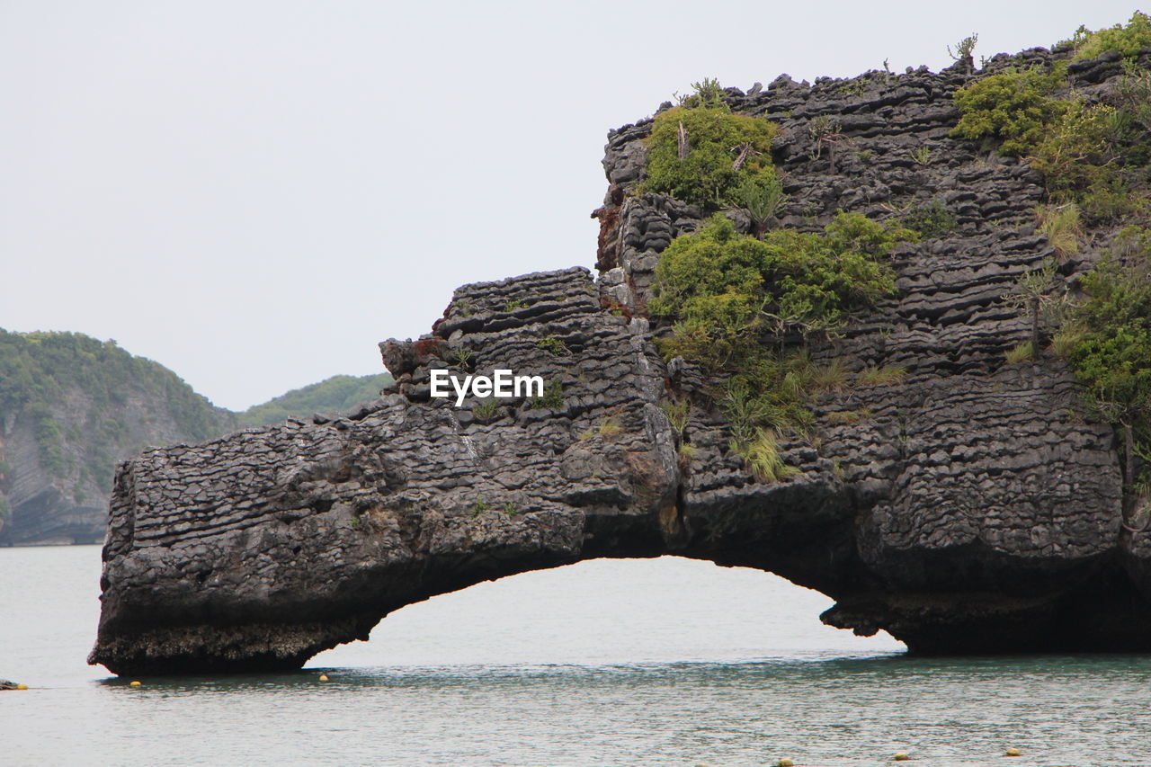 Rock formations by sea against clear sky