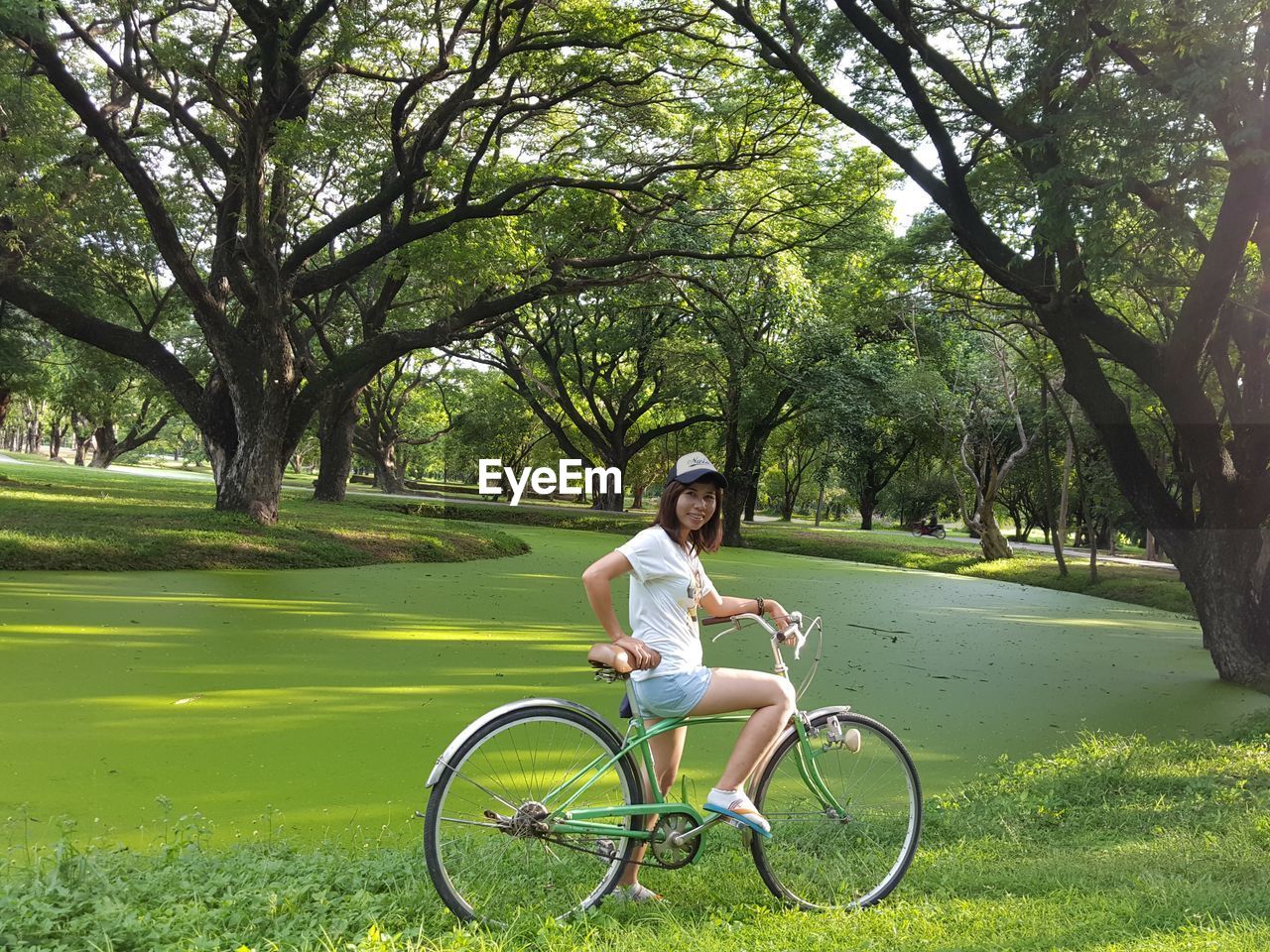 Portrait of woman sitting on bicycle against trees