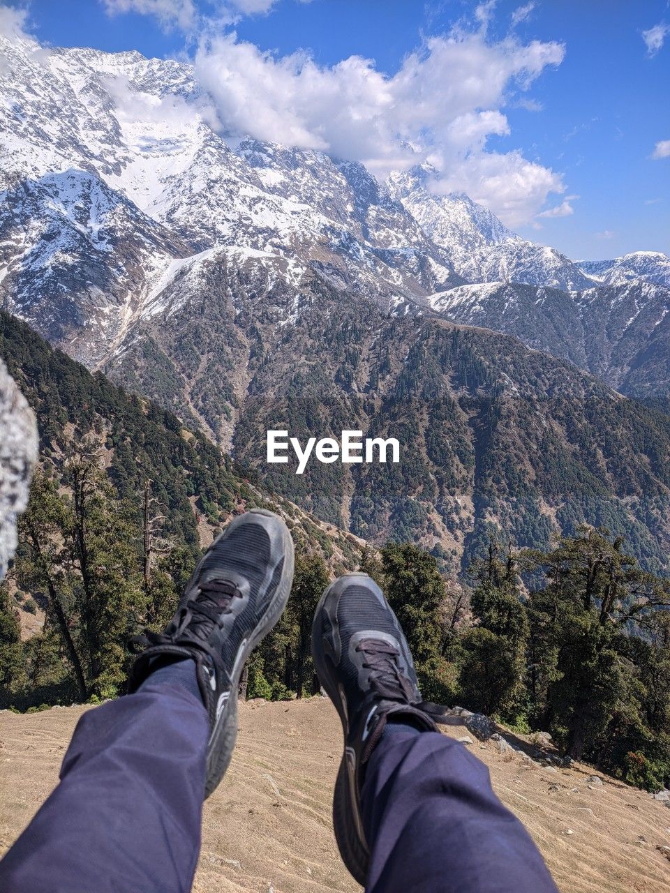 mountain, mountain range, personal perspective, scenics - nature, leisure activity, human leg, low section, beauty in nature, one person, nature, snow, walking, hiking, shoe, wilderness, environment, adventure, ridge, sky, landscape, limb, winter, lifestyles, human limb, cold temperature, day, snowcapped mountain, activity, backpacking, footwear, outdoors, cloud, travel, travel destinations, human foot, men, land, summit, holiday, adult, vacation, non-urban scene, trip, tranquil scene, plant, mountain pass, tree, mountain peak, sunlight, blue, tourism, tranquility, rock, standing, relaxation, sports, mountaineering, valley