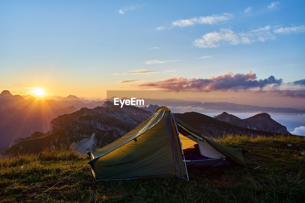 Tent on mountain against sky during sunset