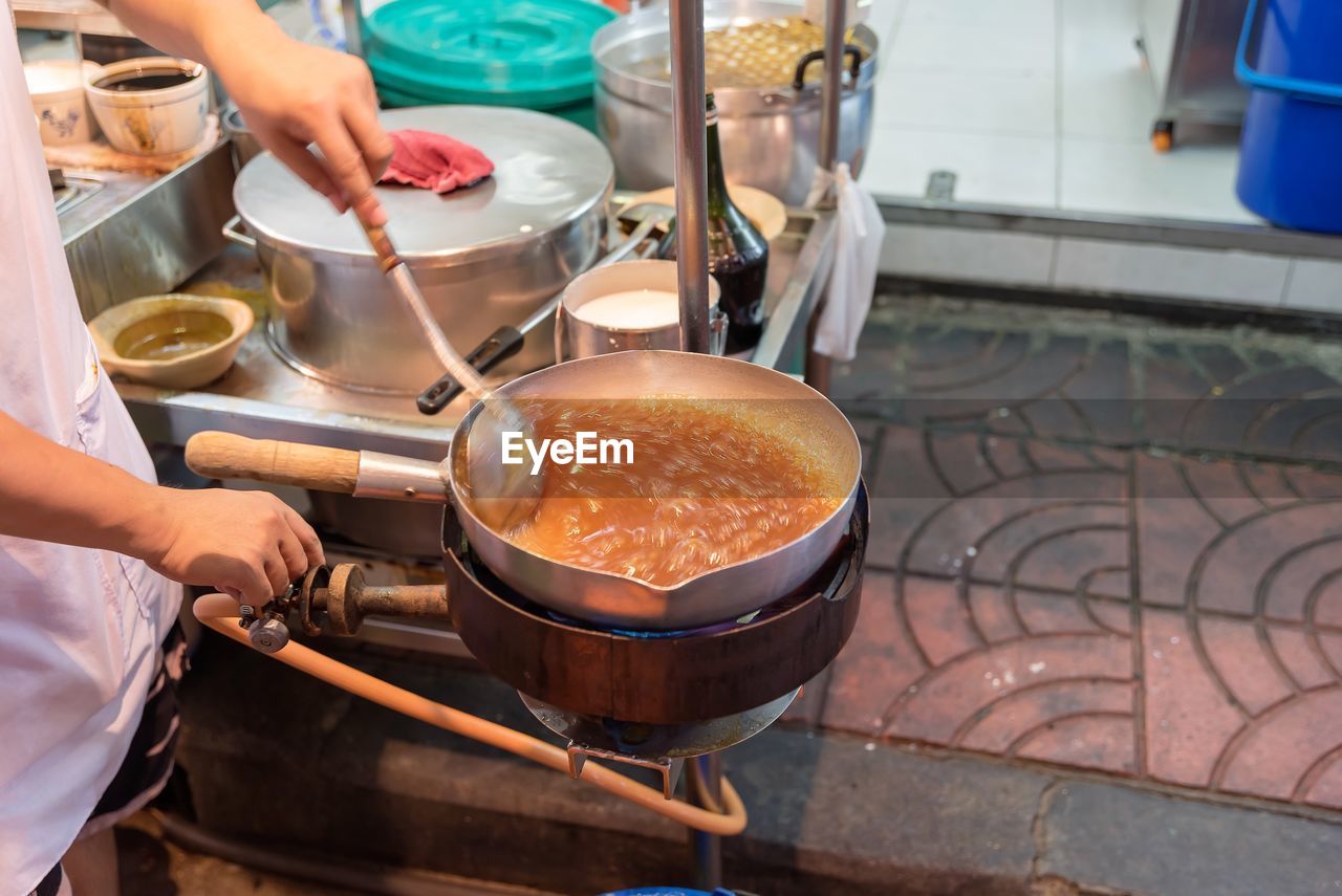 MIDSECTION OF PERSON PREPARING FOOD IN KITCHEN