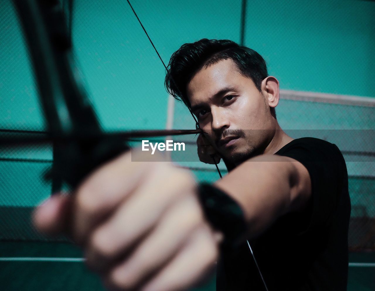 Portrait of young man holding bow and arrow