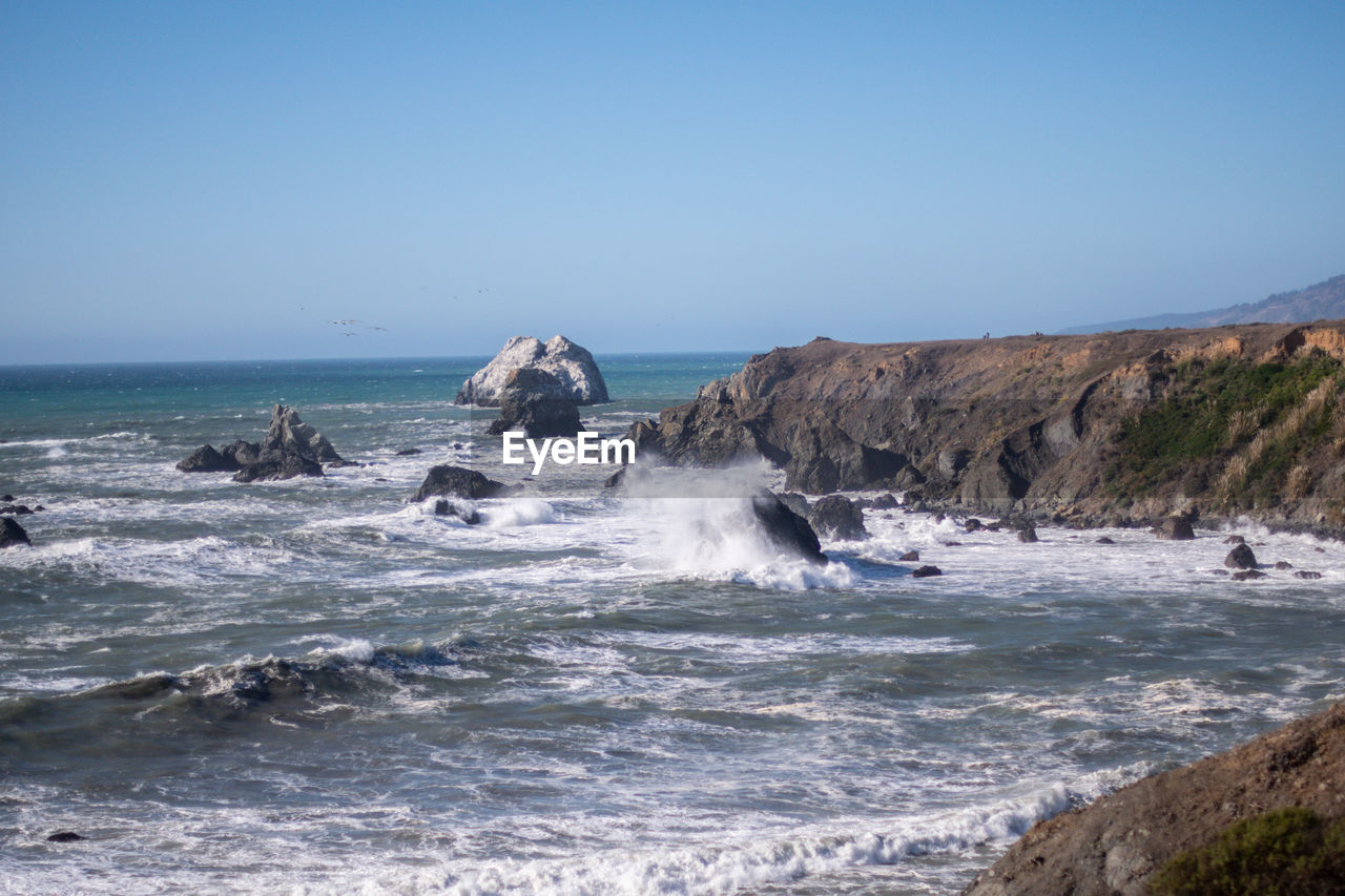 SCENIC VIEW OF ROCKS ON SEA AGAINST CLEAR SKY