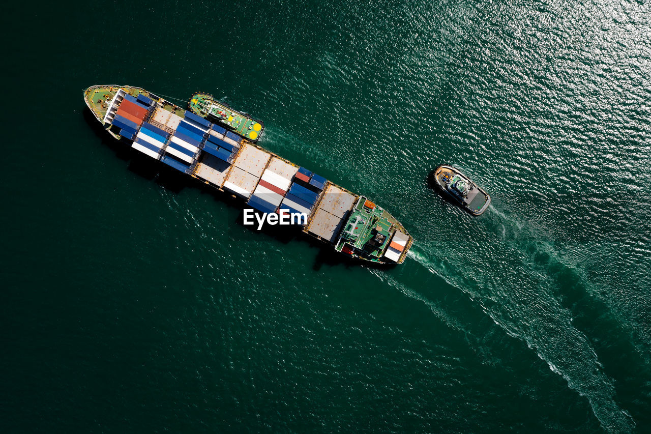 Aerial top view container ship sailing on the green sea full speed container for logistics, 