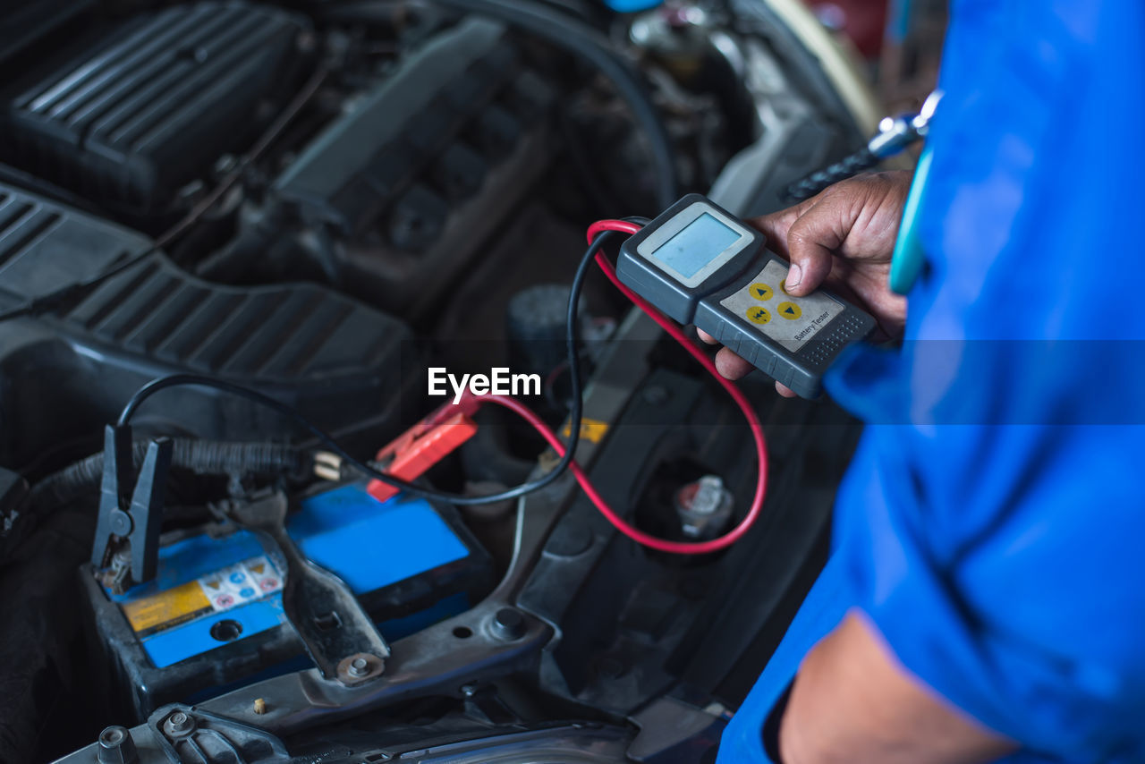 midsection of man using car engine