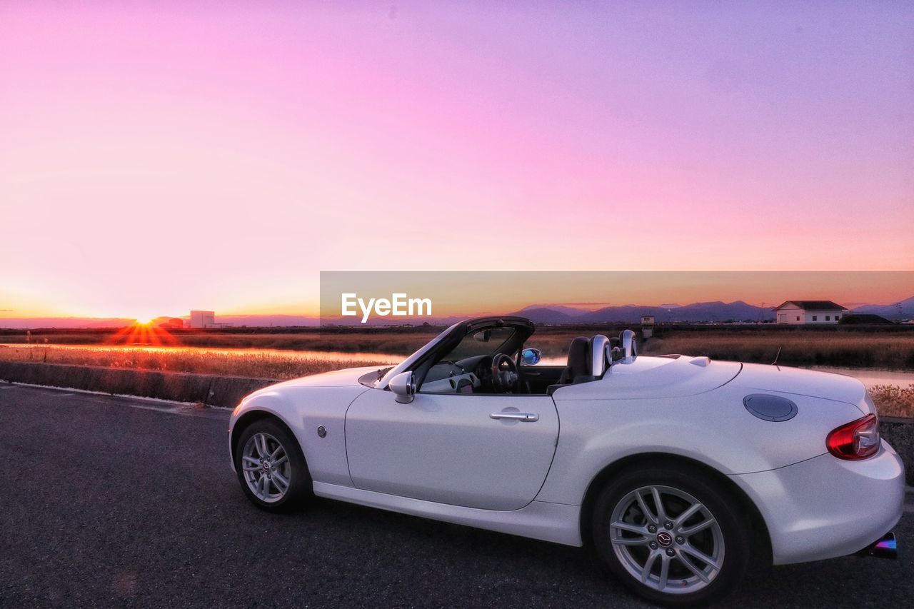 CARS ON ROAD AGAINST SKY AT SUNSET