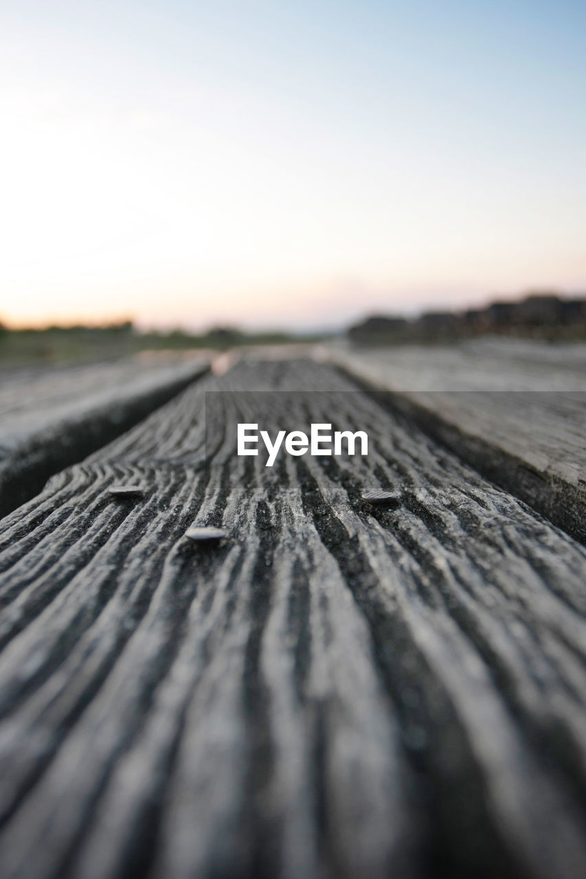 Surface level on wooden table against sky