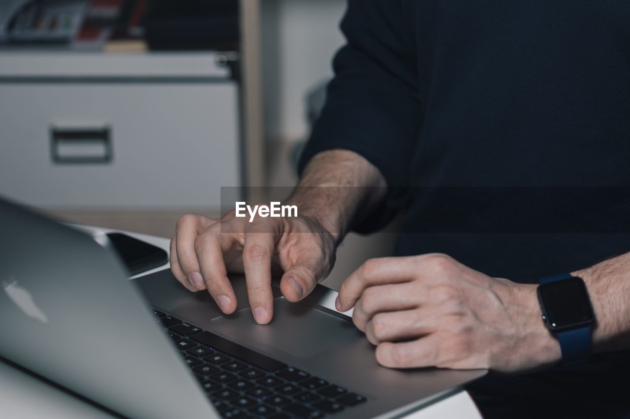 MIDSECTION OF MAN USING LAPTOP