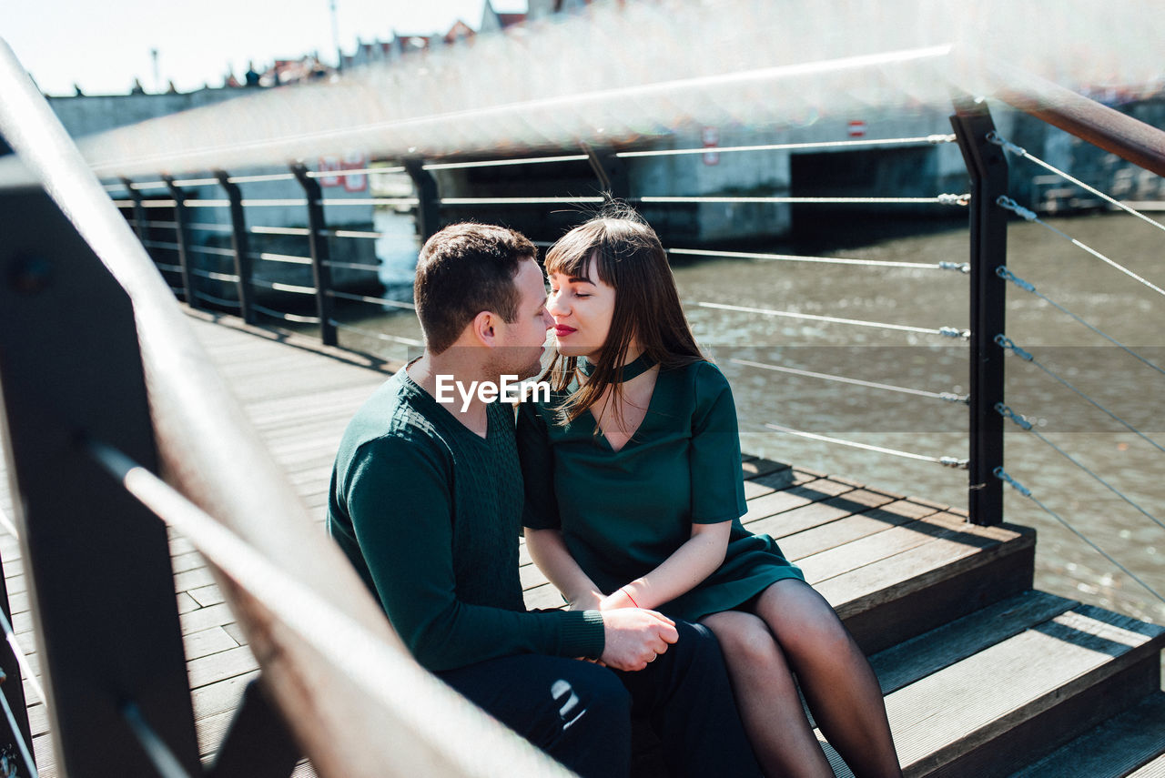 COUPLE SITTING ON RAILING