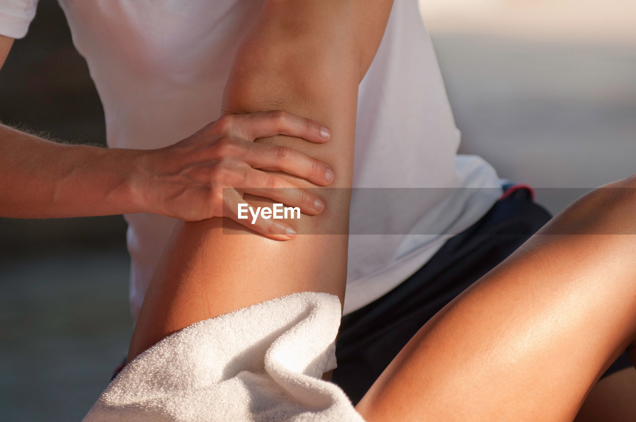 Midsection of masseuse giving massage on leg of woman