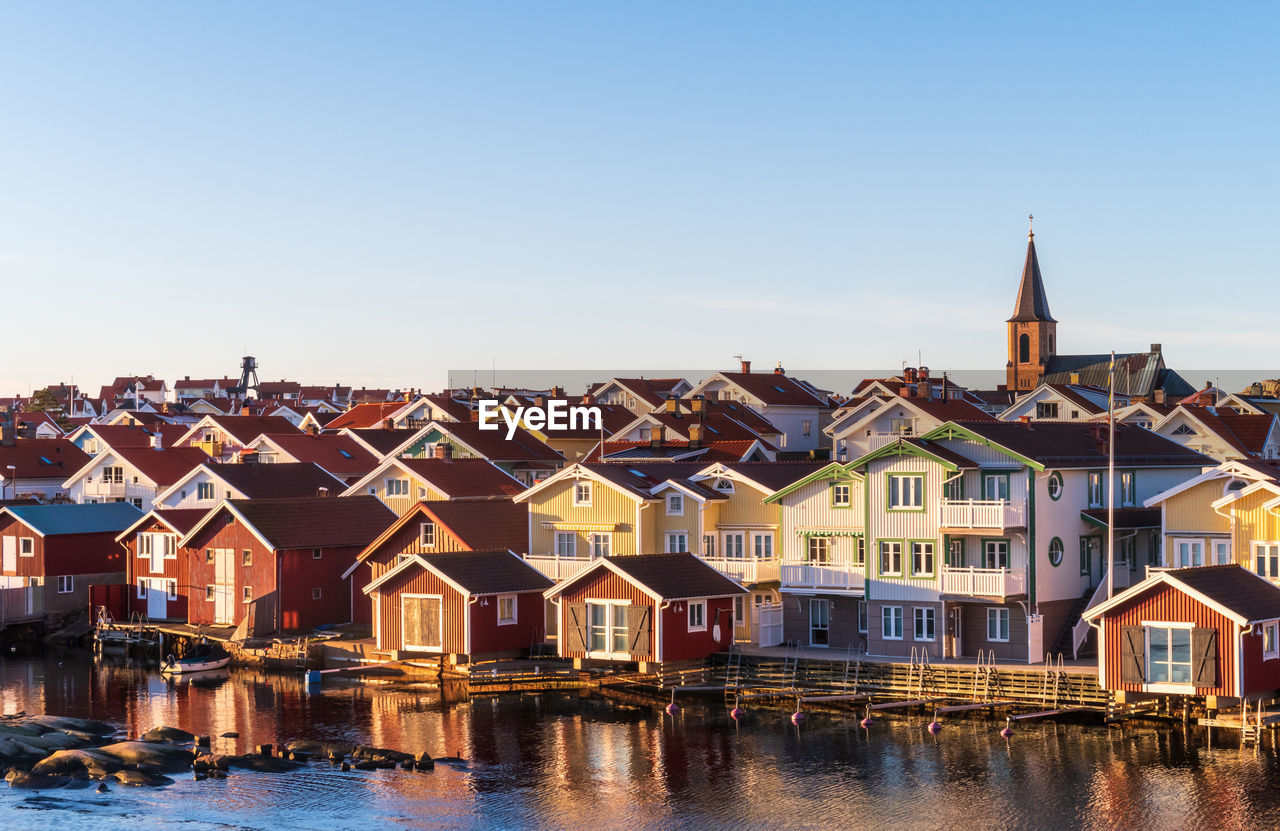 High angle view houses by river and buildings in town against sky