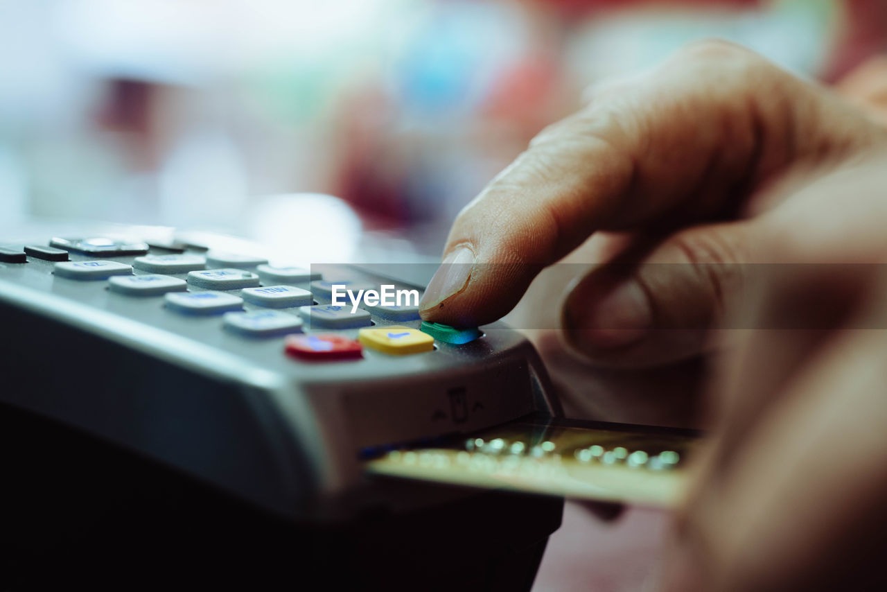 Cropped hand of man using credit card for payment in store