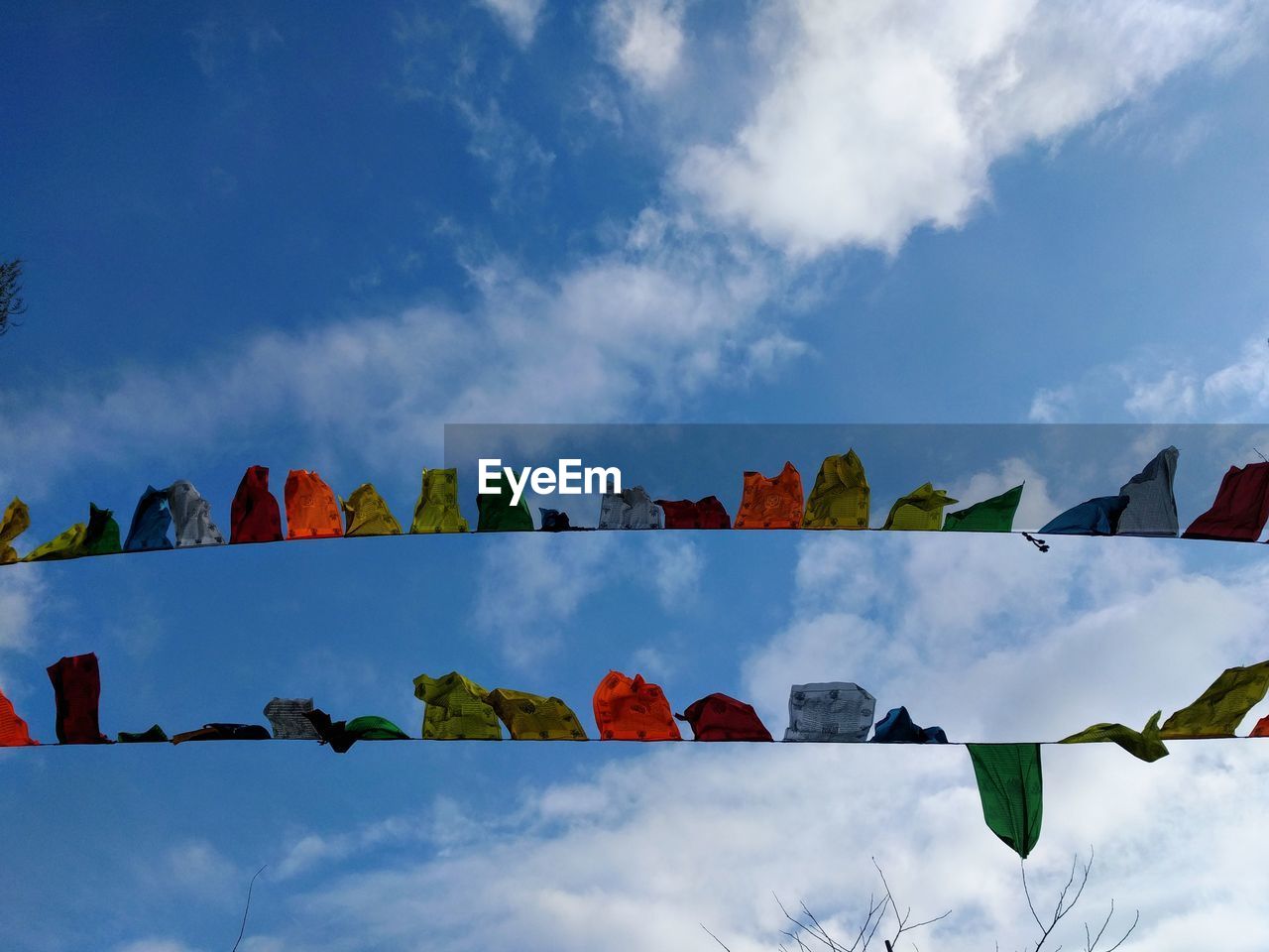 Directly below shot of bunting flags against cloudy sky