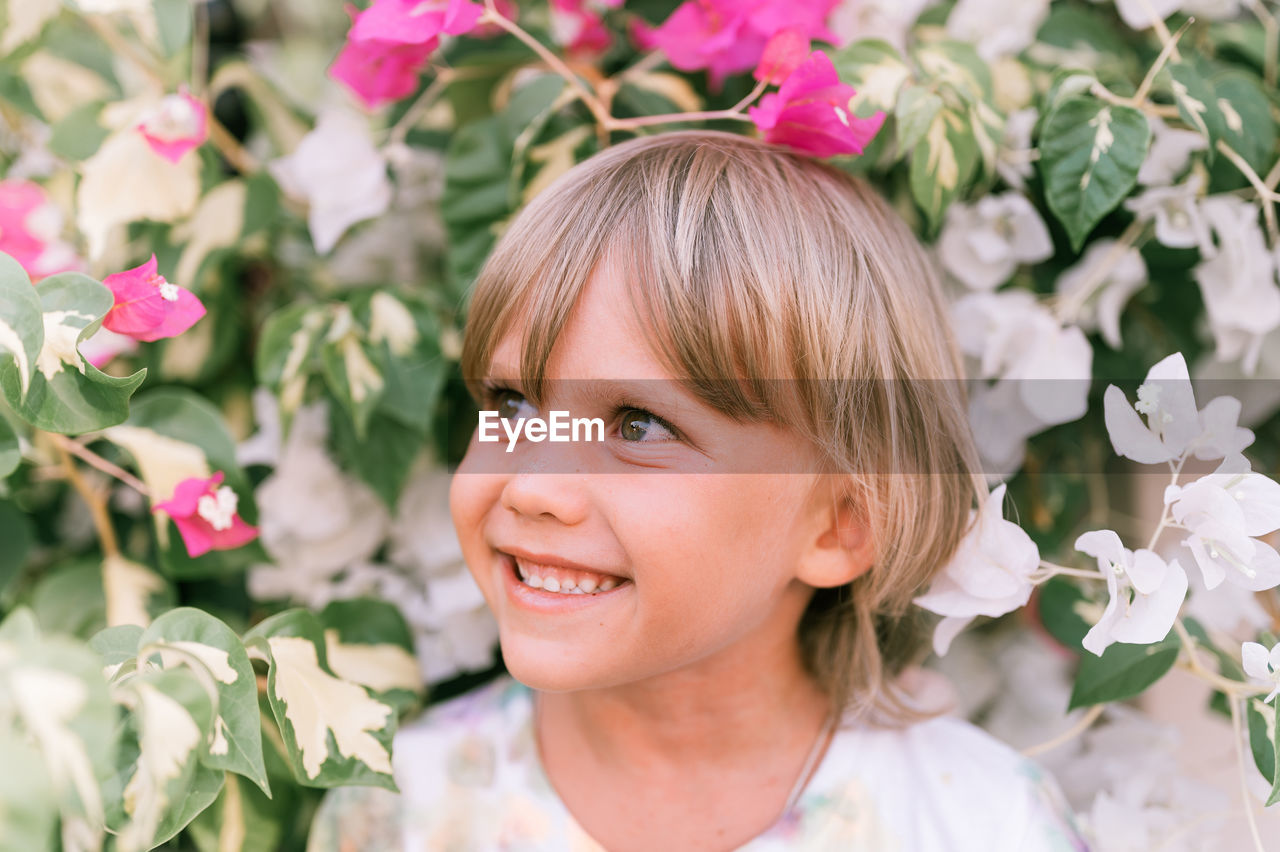 Portrait of face of a candid little happy smiling five year old blonde kid boy with green eyes